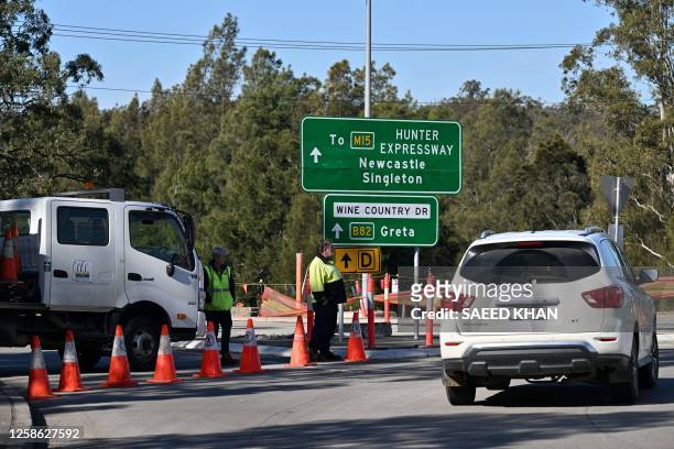 People stand by a roadblock some 500 meters from the site of a bus crash, where 10 people from a wedding party were killed, in Cessnock, in...