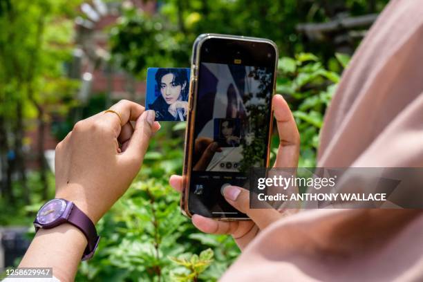 Fan takes a picture of a photo of Kim Tae-hyung, also known professionally as V, a member of K-pop group BTS, in Seoul on June 12 on the occasion of...