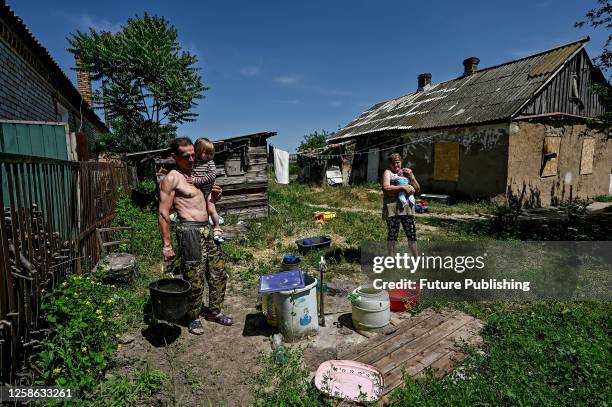 Man, woman and children are seen in the yard by the buckets with water as locals stock up on drinking and technical water after the Khakhovka Dam was...