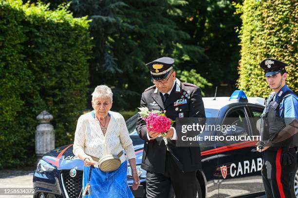 Carabinieri officer assists a mourner as she arrives to lay flowers outside Villa San Martino, the residence of Italian businessman and former prime...