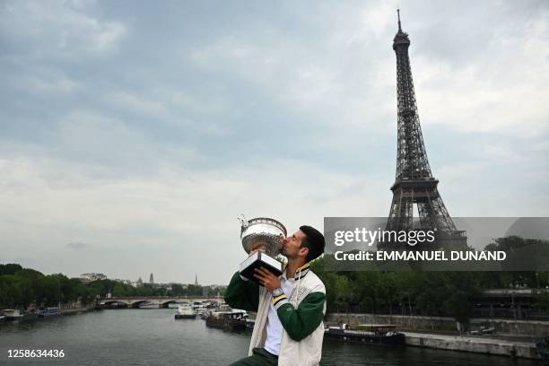 Serbia's Novak Djokovic kisses the Musketeers' Trophy, as the Eiffel Tower is seen in the background, during a photocall after winning the...