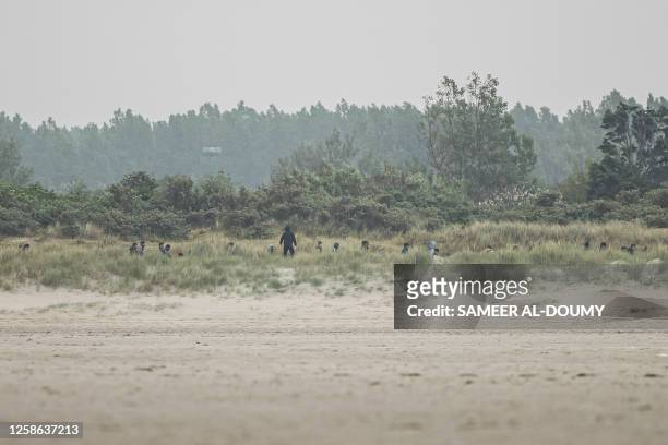 Migrants hide in the dunes before attempting to board smugglers' boats to Britain from Gravelines, northern France on June 12, 2023. At dawn on June...