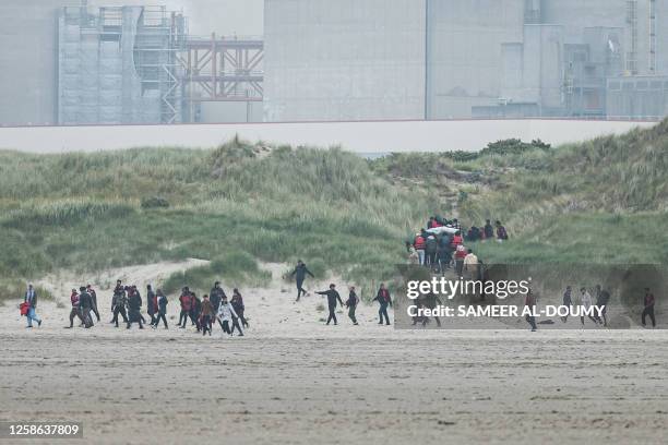 Migrants run up the dunes near Gravelines Nuclear Power Station to hide the smuggling boats from French National Police dispatched to prevent them...