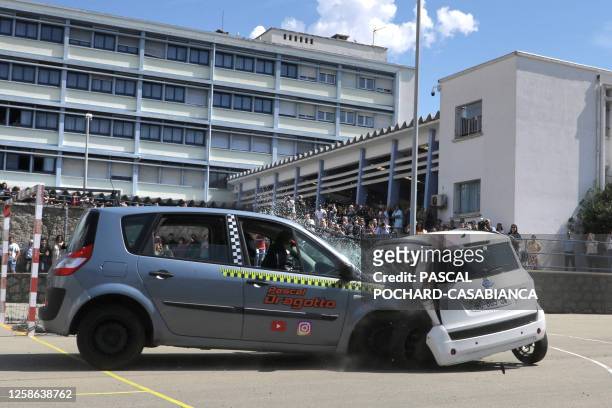 This photograph taken on June 12, 2023 shows school children looking on as a car impacts a microcar "voiture sans permis", a EU vehicle designed to...