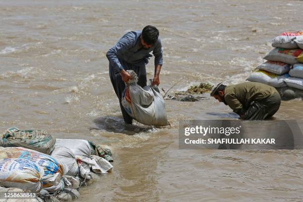 Afghan men place sand bags as they prepare a wall to prevent from flood waters in a river, in the Alingar district of Laghman province on June 12,...