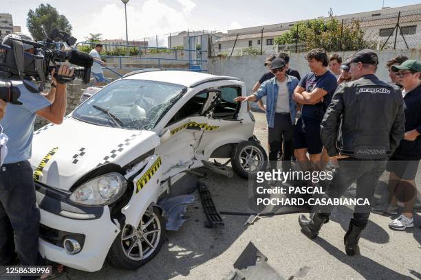 Students and media examine the damage caused to a microcar "voiture sans permis", a EU vehicle designed to less stringent requirements when compared...