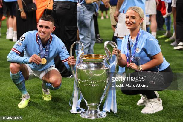 Phil Foden of Manchester City and Rebecca Cooke pose with the trophy after the UEFA Champions League 2022/23 final match between Manchester City FC...