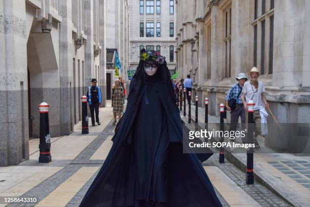 Climate activist wearing a black costume, known as an Oil Slicker, performs in Guildhall during the protest. Extinction Rebellion staged a...