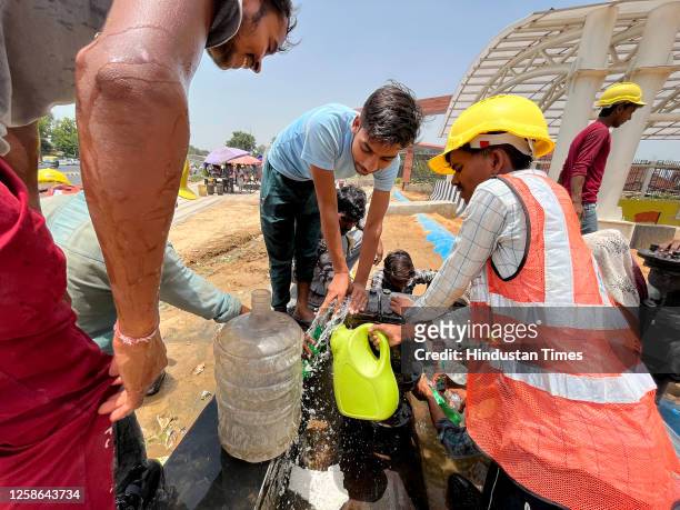 Workers in long queue filling water bottles at lunch time on a harsh sunny day during heat waves near Pragati Maidan, on June 12, 2023 in New Delhi,...
