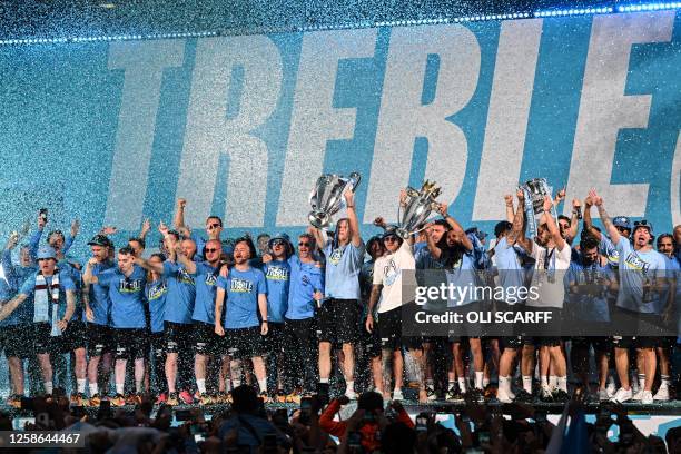 Manchester City's players celebrate on stage with their trophies following an open-top bus victory parade for their European Cup, FA Cup and Premier...