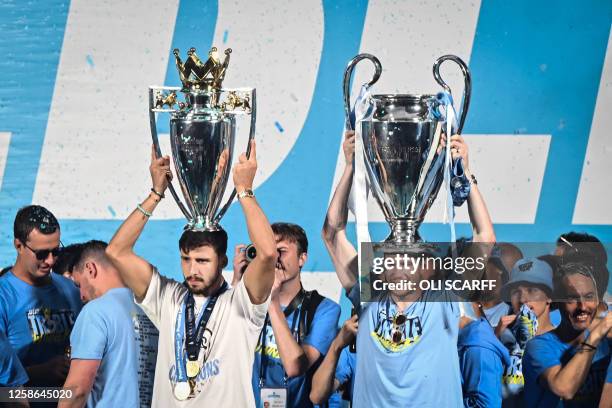 Manchester City's Portuguese defender Ruben Dias and Manchester City's Belgian midfielder Kevin De Bruyne celebrate with their trophies on stage...