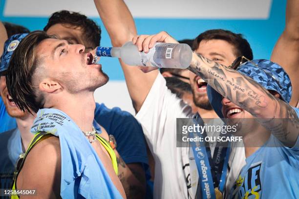 Manchester City's English midfielder Kalvin Phillips pours alcohol in the mouth of Manchester City's English midfielder Jack Grealish as they...