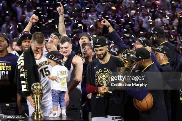 Nikola Jokic of the Denver Nuggets is presented with the Bill Russell Finals MVP Trophy while Jamal Murray holds the Larry O'Brien Championship...