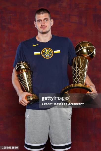 Nikola Jokic of the Denver Nuggets poses for a portrait with the Larry O'Brien Trophy and the Bill Russell Finals MVP Trophy after winning Game Five...