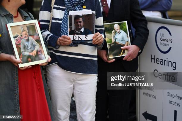 Members of the Covid-19 Bereaved Families for Justice hold photos of relatives who died during the pandemic, as they demonstrate outside the venue...