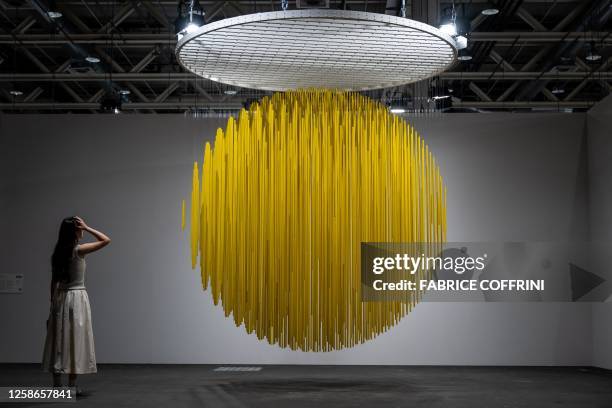 Visitor watches "Esfera Amarilla" 1984, painted metal and nylon thread by late Venezuelan artist Jesus Rafael Soto displayed at the Art Basel fair...