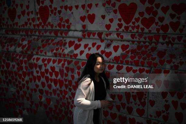 Pedestrian walks past messages and hearts on the National Covid Memorial Wall, dedicated to those who lost their lives to Covid-19, on the embankment...