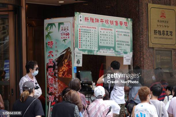 People are lining up to buy zongzi in front of Xinya Food, a time-honored store on Nanjing Road Pedestrian Street in Shanghai, China, on June 12...