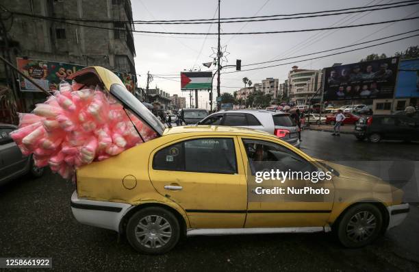 Car carry cotton candy along a street in Gaza City on June 13, 2023.