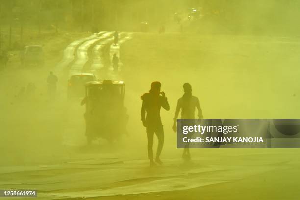 People commute along a road during a sand storm at the Sangam, the confluence of the rivers Ganges, Yamuna and mythical Saraswati on a hot summer day...