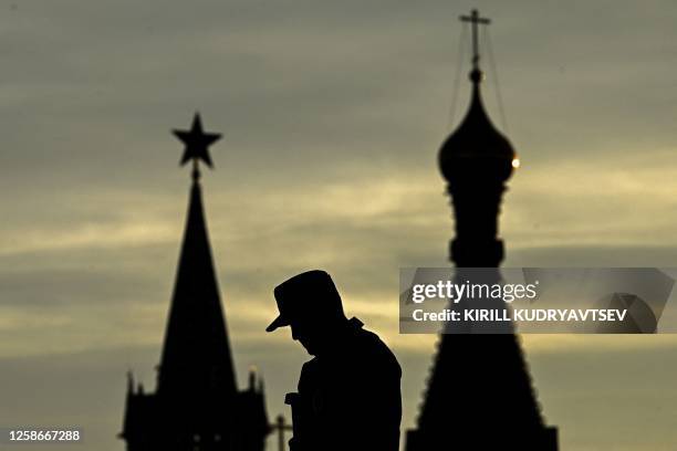 Security officer walks in Zaryadye park in front of the Kremlin's Spasskaya Tower and St Basil's cathedral during sunset in downtown Moscow on June...