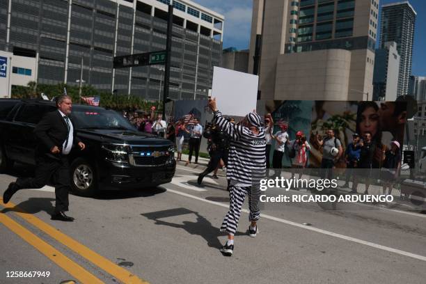 Demonstrator runs in front of a motorcade of vehicles carrying former US President Donald Trump, at Wilkie D. Ferguson Jr. United States Federal...