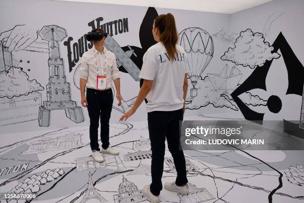 Stand staff member observes a man wearing a virtual-reality headset at the Louis Vuitton stand at the Vivatech technology startups and innovation...