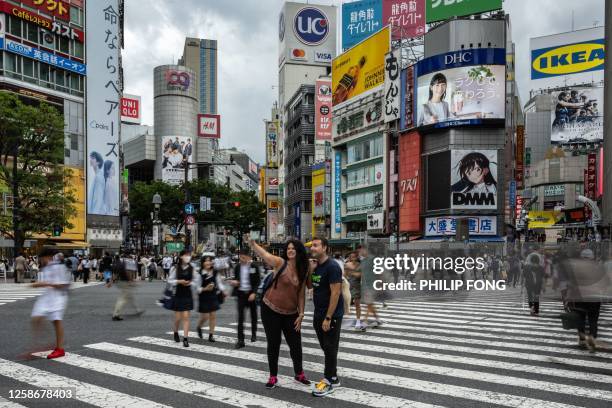 People take pictures at the "Shibuya Crossing" in the Shibuya district of Tokyo on June 14, 2023.