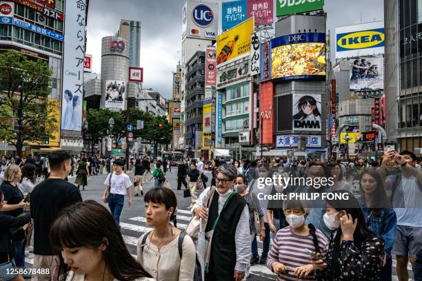 People walk across "Shibuya Crossing" in the Shibuya district of Tokyo on June 14, 2023.