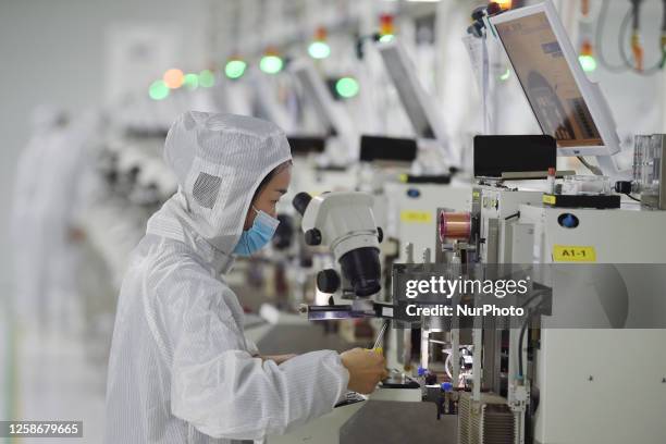 Worker wearing a mask and protective clothing makes chips in a dust-free workshop at a semiconductor company in Suqian, Jiangsu province, Feb 28,...