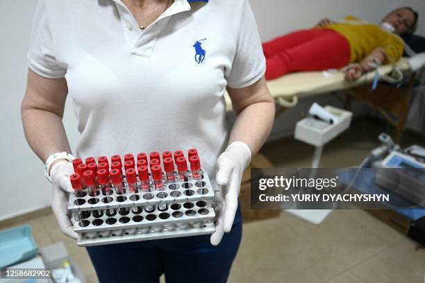 Medical staff holds samples of blood as people donate blood for the military on World Blood Donor Day as part of the charity event "Become a blood...