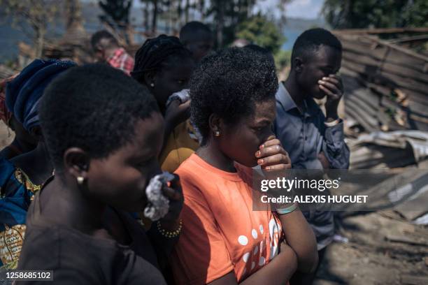 Residents cover their noses to protect themselves from the smell of a corpse being pulled from the rubble of a house destroyed by a landslide in the...