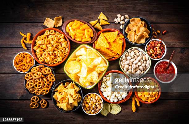 salty snacks assortment shot from above on rustic wooden table - snack bowl stock pictures, royalty-free photos & images