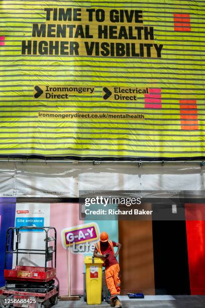 Construction site traffic marshall is seen below a large banner that mentions mental health in the construction workplace, an industry that sees 687...