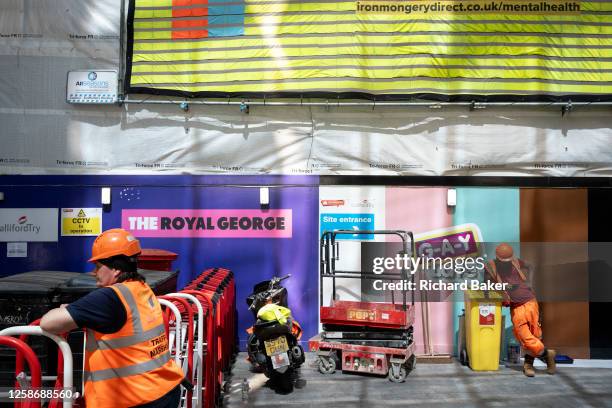 Construction site traffic marshall is seen below a large banner that mentions mental health in the construction workplace, an industry that sees 687...