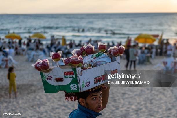 Vendor selling candy apples looks for customers on a beach in Gaza City on June 14, 2023.