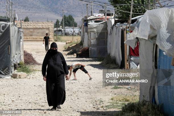 In this picture taken on June 13 a Syrian woman walks between tents at a refugee camp in Saadnayel in eastern Lebanon's Bekaa Valley. Lebanese...