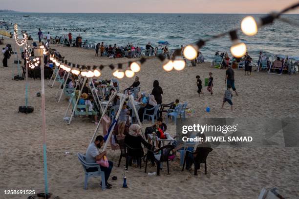 Families sit along a beach in Gaza City on June 14, 2023.