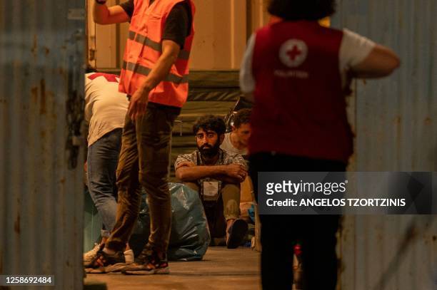 Survivor of a shipwreck sits inside a warehouse next to medical personnel at the port in Kalamata town, on June 14 after a boat carrying dozens of...