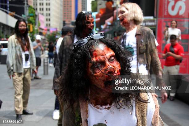 Person dressed as a "walker" wanders through the crowd as they participate in a zombie walk to promote the release of the TV series "The Walking...