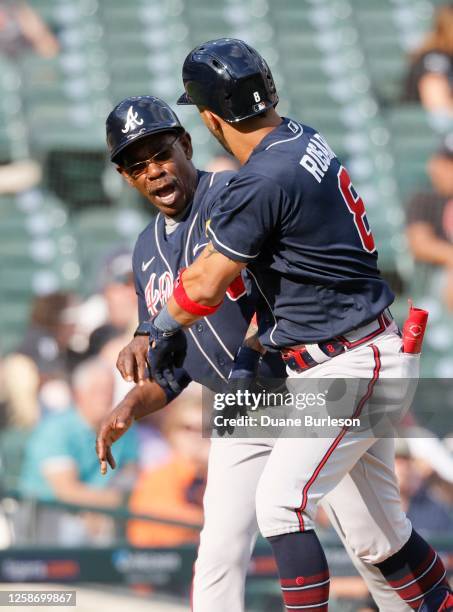 Eddie Rosario of the Atlanta Braves celebrates with third base coach Ron Washington after hitting a solo home run against the Detroit Tigers during...