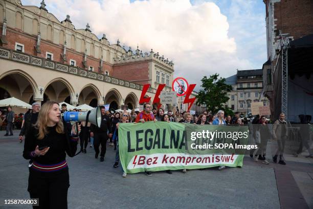 Protesters hold a banner and symbols of Women's Strikes: black umbrellas, lightning strikes, and hangers during the demonstration against the...