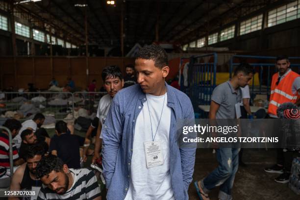 Survivor stands as other survivors of a shipwreck sit inside a warehouse at the port in Kalamata town, on June 15 after a boat carrying migrants sank...