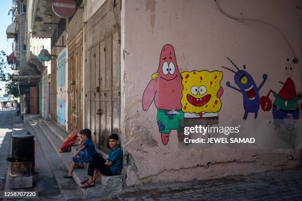 Children boil corn beside a street in Gaza City on June 15, 2023.