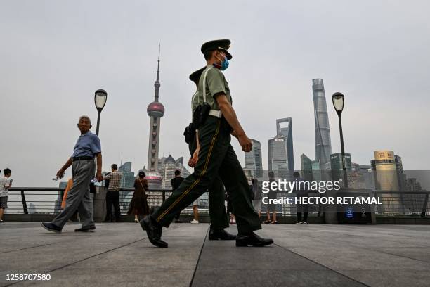 Chinese paramilitary police walk on the Bund promenade along the Huangpu river in the Huangpu district in Shanghai on June 15, 2023.