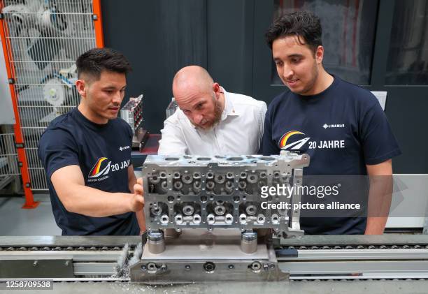June 2023, Saxony, Crimmitschau: Zia Sahel , employee from Afghanistan, Enrico Held, plant manager Linamar Antriebstechnik GmbH, and Zakaria Raffali,...