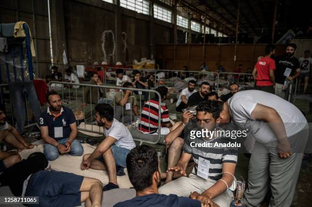 Rescued immigrants of a shipwreck after a boat carrying dozens of migrants sank in international waters of Ionian Sea, sit inside a warehouse in...