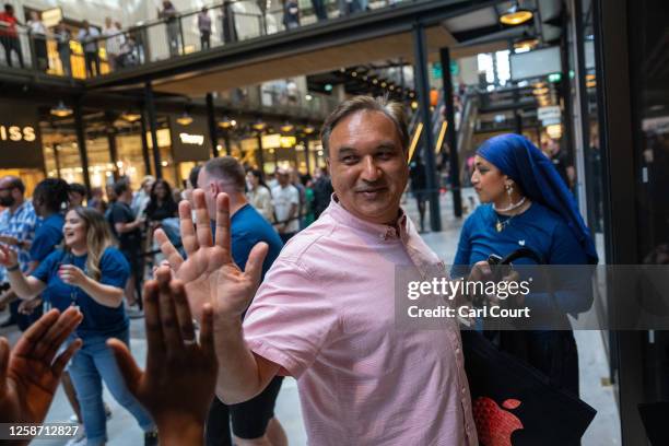 Man high fives staff as he enters the new Apple Store in Battersea Power Station on June 15, 2023 in London, England. Apple Battersea will be...