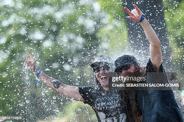 Heavy metal fans react and gesture under a water curtain during the Hellfest Summer Open Air rock festival in Clisson, western France, on June 15,...