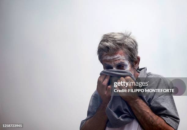 Demonstrator protects his face from teargas thrown by riot police in front of the Greek parliament on June 29, 2011 during a 48-hour general strike...